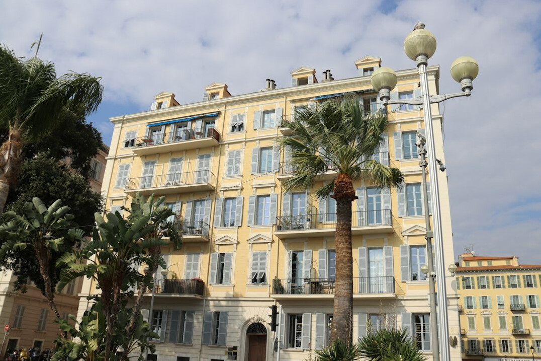 Grand French Riviera house facade with palm trees and wrought iron gate