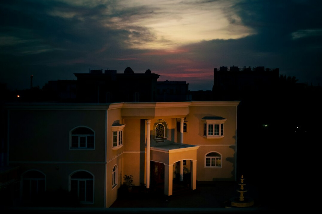 Elegant Riviera-style villa facade lit at dusk with warm window light